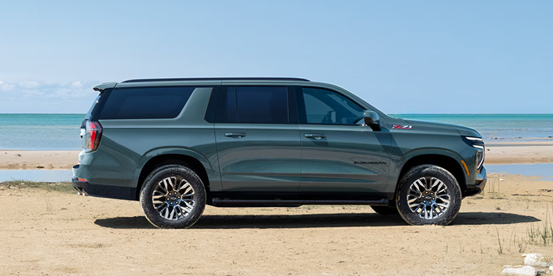 Green full-size SUV parked by the beach.